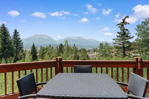 Eine Terrasse mit Tisch und Stühlen mit Blick auf eine gebirgige Landschaft.