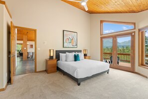 A bedroom with a large bed, a ceiling fan, a painting, and a view through the window. - Spacious Mountain Home, Private Deck, Central Location in Dillon (Dillon)