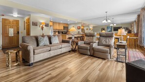 Uma sala de estar espaçosa com sofá, poltrona reclinável e área de jantar com mesa e cadeiras.