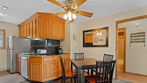 A kitchen with wooden cabinets, a refrigerator, a coffee maker, and a dining table with chairs. - Cozy Dillon Home: Skiing, Fishing, & Lakefront Living (Dillon)