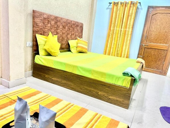 Una cama con cabecera de madera, almohadas amarillas y colcha verde.