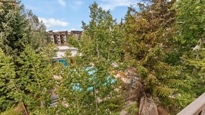 A residential area with a pool, trees, and a multi-story building in the background. - Sleeps 7: Resort-Style Keystone Condo w/ Private Balcony (Keystone)
