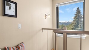 A room with a large window, a framed picture on the wall, a light fixture, and a patterned pillow. - Sleeps 7: Resort-Style Keystone Condo w/ Private Balcony (Keystone)