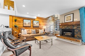 Un salon moderne avec une cheminée, des murs en bois, un canapé, une table basse et un fauteuil en cuir.