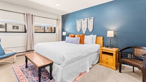 A hotel room with a large bed, a bedside table with a lamp, a chair, a bench, and a view of the outside. - Sleeps 7: Resort-Style Keystone Condo w/ Private Balcony (Keystone)