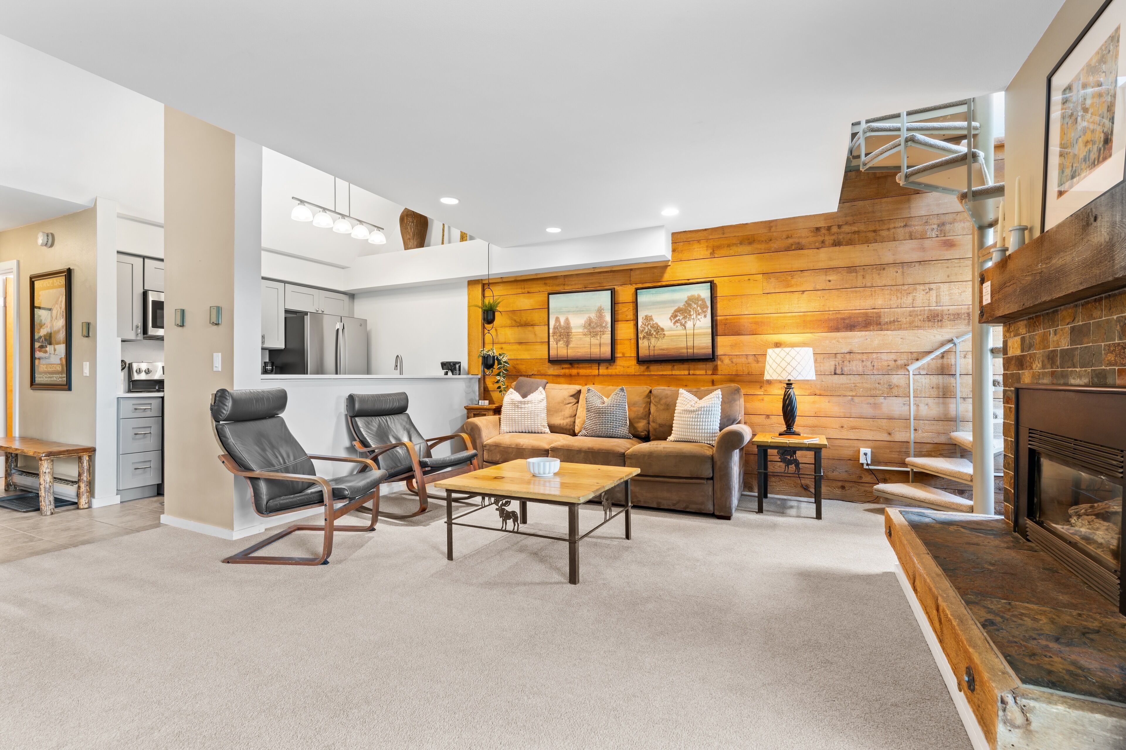 Un salon moderne avec une cheminée, un canapé, deux fauteuils et une table basse.
