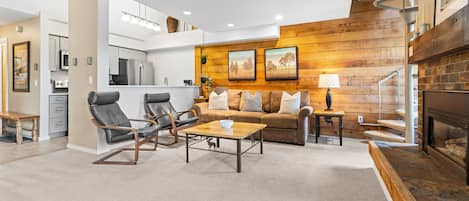 A modern living room with a fireplace, a sofa, two armchairs, and a coffee table.