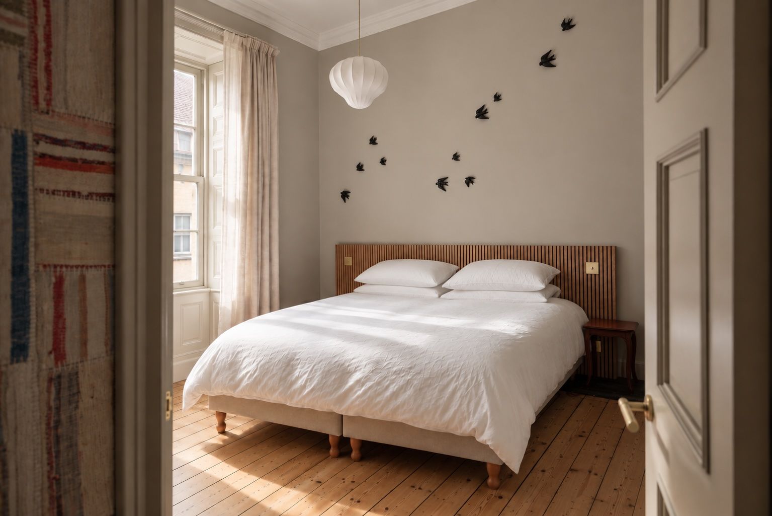 Un dormitorio con una cama grande, cabecera de madera y una lámpara fijada a la pared.