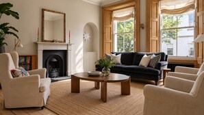 A living room with a fireplace, a black sofa, a round coffee table, and a bookshelf.