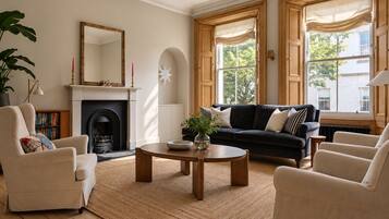 A living room with a fireplace, a black sofa, a round coffee table, and a bookshelf.