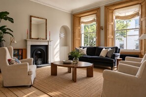 A living room with a fireplace, a black sofa, a round coffee table, and a bookshelf.