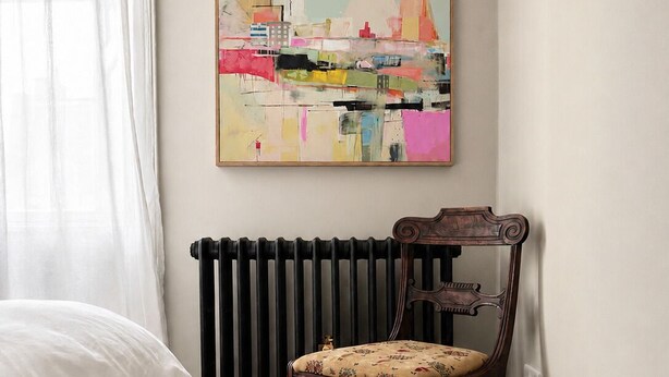 A bedroom with a bed, a chair, a radiator, and a painting on the wall.