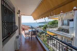 Un balcon avec vue sur la mer, une table avec des chaises et une rambarde.