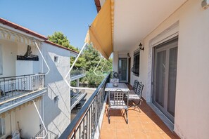 A balcony with a table and chairs, a sliding glass door, and a view of neighboring buildings.