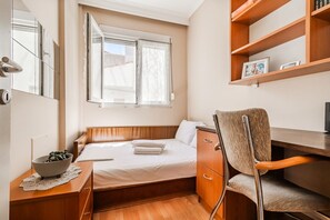 A compact hotel room with a bed, a desk, a chair, a bedside table with a bowl, and a window. - Tilias House by Rentals Pro - Nea Flogita Halkidiki (Nea Flogita)