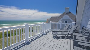 Una terraza de madera con barandas blancas que da a una playa y al océano.