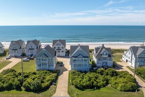 A coastal residential area with multiple two-story houses featuring gabled roofs and front porches. - Oceanfront pool, hot tub and game room (North Topsail Beach)