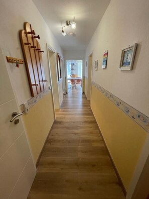 A hallway with wooden flooring, white walls, and a ceiling light fixture. - 10 Vacation Rental "Anders Fewo 1" (Burg auf Fehmarn)