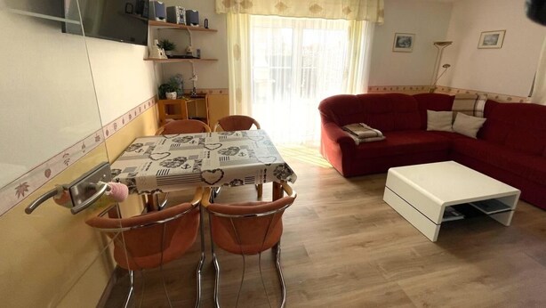 Ein Essbereich mit einem Tisch, Stühlen und einem roten Sofa.