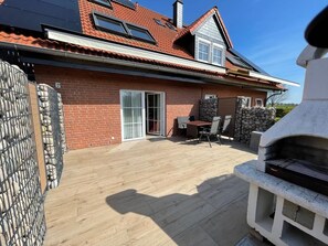 A brick house with a tiled roof, a patio with a grill, and a stone wall. - 10 Vacation Rental "Anders Fewo 1" (Burg auf Fehmarn)