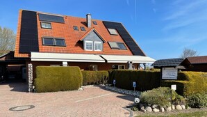 Ein Gebäude mit einem geneigten Dach, Solaranlagen und einer gepflasterten Auffahrt zu einem verschlossenen Eingang.