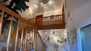 Un intérieur à plusieurs niveaux, avec un escalier en bois, un coin cuisine et un espace repas.