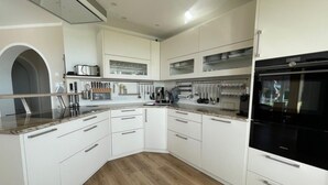 Une cuisine moderne avec des meubles blancs, un four encastré et un plan de travail en granit.
