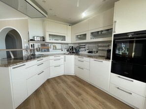 A modern kitchen with white cabinetry, a built-in oven, and a granite countertop. - 30 Vacation Rental "Anders Fewo 4" (Burg auf Fehmarn)