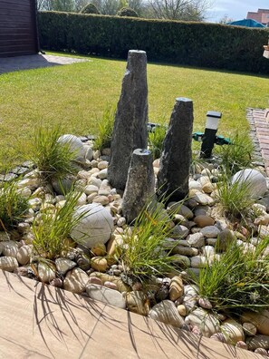 A garden with a stone pathway, rocks, and grass. - 30 Vacation Rental "Anders Fewo 4" (Burg auf Fehmarn)