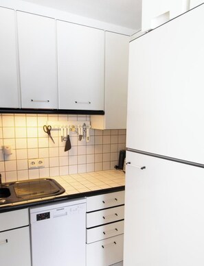 Eine Küche mit weißen Schränken, einem Geschirrspüler und einer Arbeitsfläche mit Spüle.