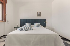 Una habitación de hotel con una cama grande, una mesita de noche, una lámpara y una ventana.