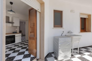 A kitchen with a checkered floor, a sink, and a window with blinds.
