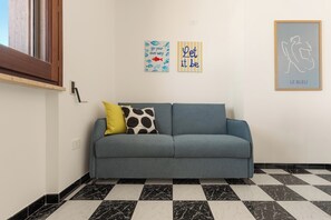 A room with a grey sofa, two cushions, a black and white checkered floor, and three wall art pieces. - Casa Tramonti - Trilo Comfort by BarbarHouse (Santa Maria di Leuca)