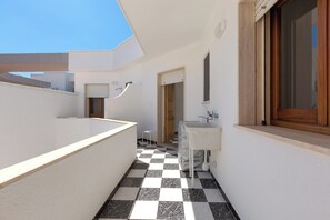 A narrow corridor with a checkered floor, a white sink, and a shower area. - Casa Tramonti - Trilo Comfort by BarbarHouse (Santa Maria di Leuca)