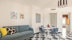 Una sala de estar moderna con un sofá azul, una mesa de comedor con sillas y un piso a cuadros.
