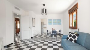 A modern living space with a checkered floor, a blue sofa with a polka dot pillow, and a dining area with a table and chairs. - Casa Tramonti - Trilo Superior by BarbarHouse (Santa Maria di Leuca)