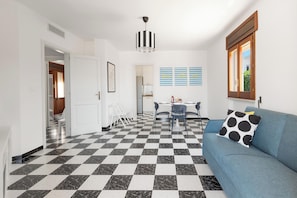 A modern living space with a checkered floor, a blue sofa with a polka dot pillow, and a dining area with a table and chairs. - Casa Tramonti - Trilo Superior by BarbarHouse (Santa Maria di Leuca)
