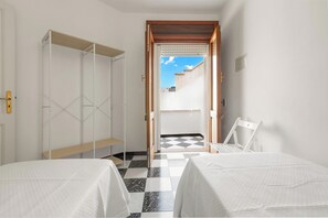 Ein Hotelzimmer mit zwei Betten, einem Kleiderschrank und Blick auf einen Innenhof.