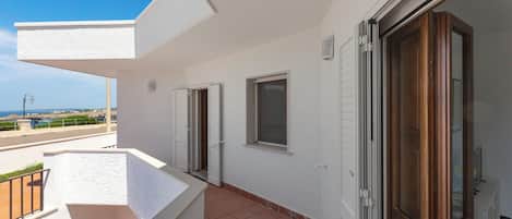 A balcony with a view of the sea, a door, and a window.