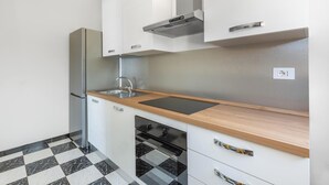 A modern kitchen with a stainless steel refrigerator, a sink, and a black stove. - Casa Tramonti - Trilo Superior by BarbarHouse (Santa Maria di Leuca)