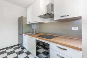 A modern kitchen with a stainless steel refrigerator, a sink, and a black stove. - Casa Tramonti - Trilo Superior by BarbarHouse (Santa Maria di Leuca)