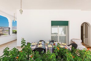 Een eethoek met een gedekte tafel, omringd door stoelen, en uitzicht op de lucht door een raam.