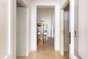 A hallway leading to a kitchen area with a dining table and chairs. - Villetta Rosa dei Venti  by BarbarHouse (Torre Colimena)