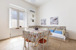 Een kamer met een eettafel, stoelen, een bank en een muur met nautische decoraties.