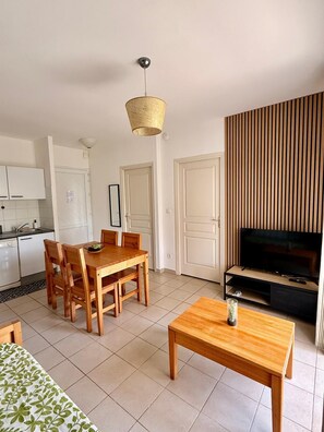 A modern living room with a dining area, a television, and a kitchen in the background. - Apartment for 4 people in a complex with a pool, direct beach access, and a restaurant. (Poggio-Mezzana)