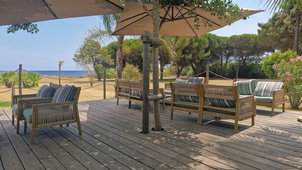 Une terrasse en bois avec des sièges extérieurs et vue sur la plage.