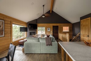Ein gemütliches Blockhauss-Interieur mit einer Couch, einem Essbereich und einer Treppe.