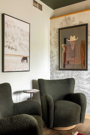 A room with a large framed painting of a cowboy, a green armchair, and a smaller framed painting of a snowy landscape. - Log Cabin Retreat - Hot Tub · Sauna · Game Room · Stunning Mountain Views (Pine)