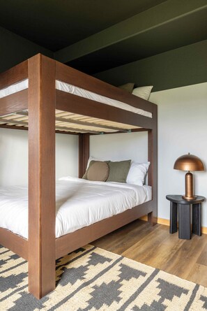 A bunk bed with a wooden frame, white bedding, and a patterned rug. - Log Cabin Retreat - Hot Tub · Sauna · Game Room · Stunning Mountain Views (Pine)