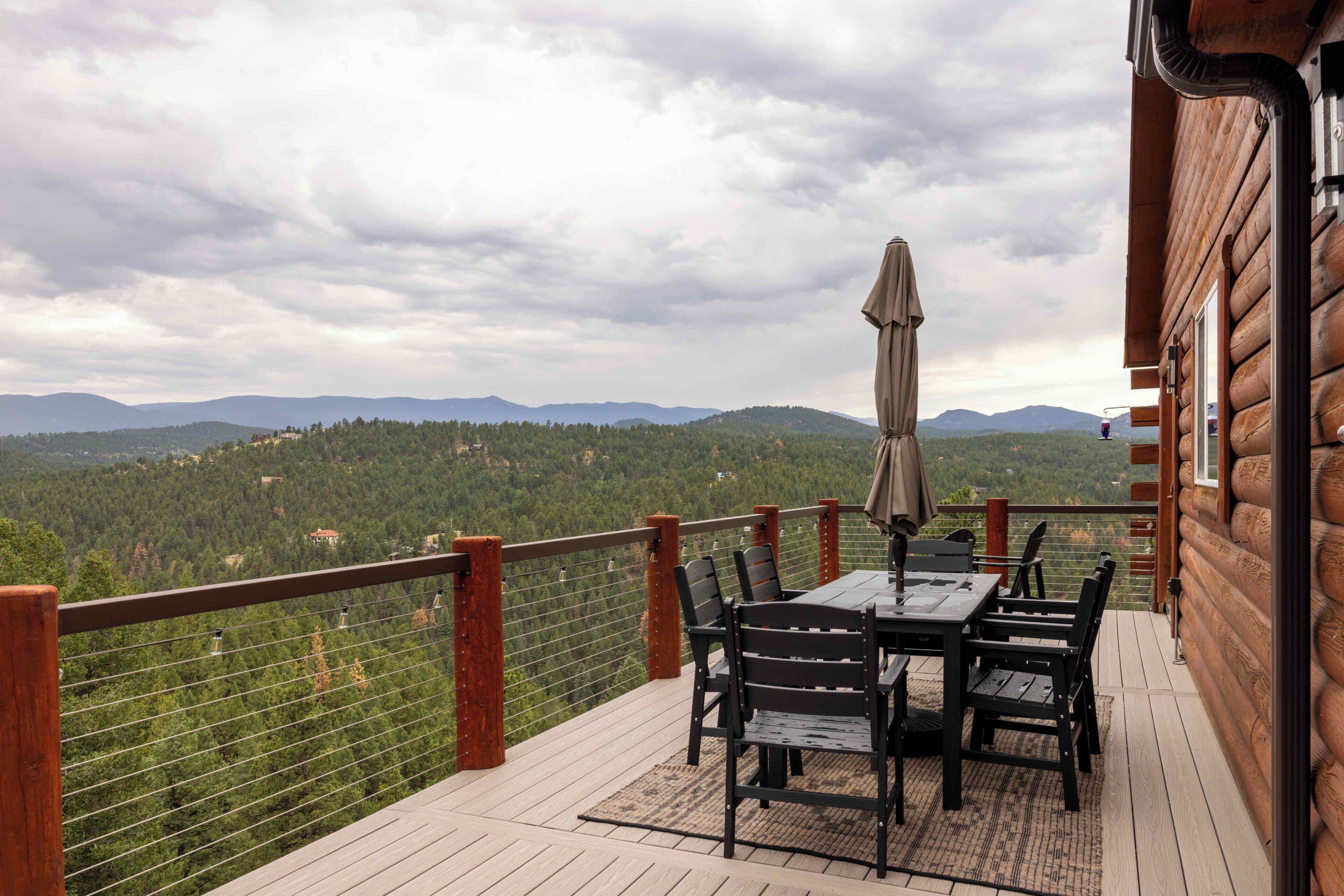 Eine Holzterrasse mit Tisch und Stühlen mit Blick auf eine gebirgige Landschaft.